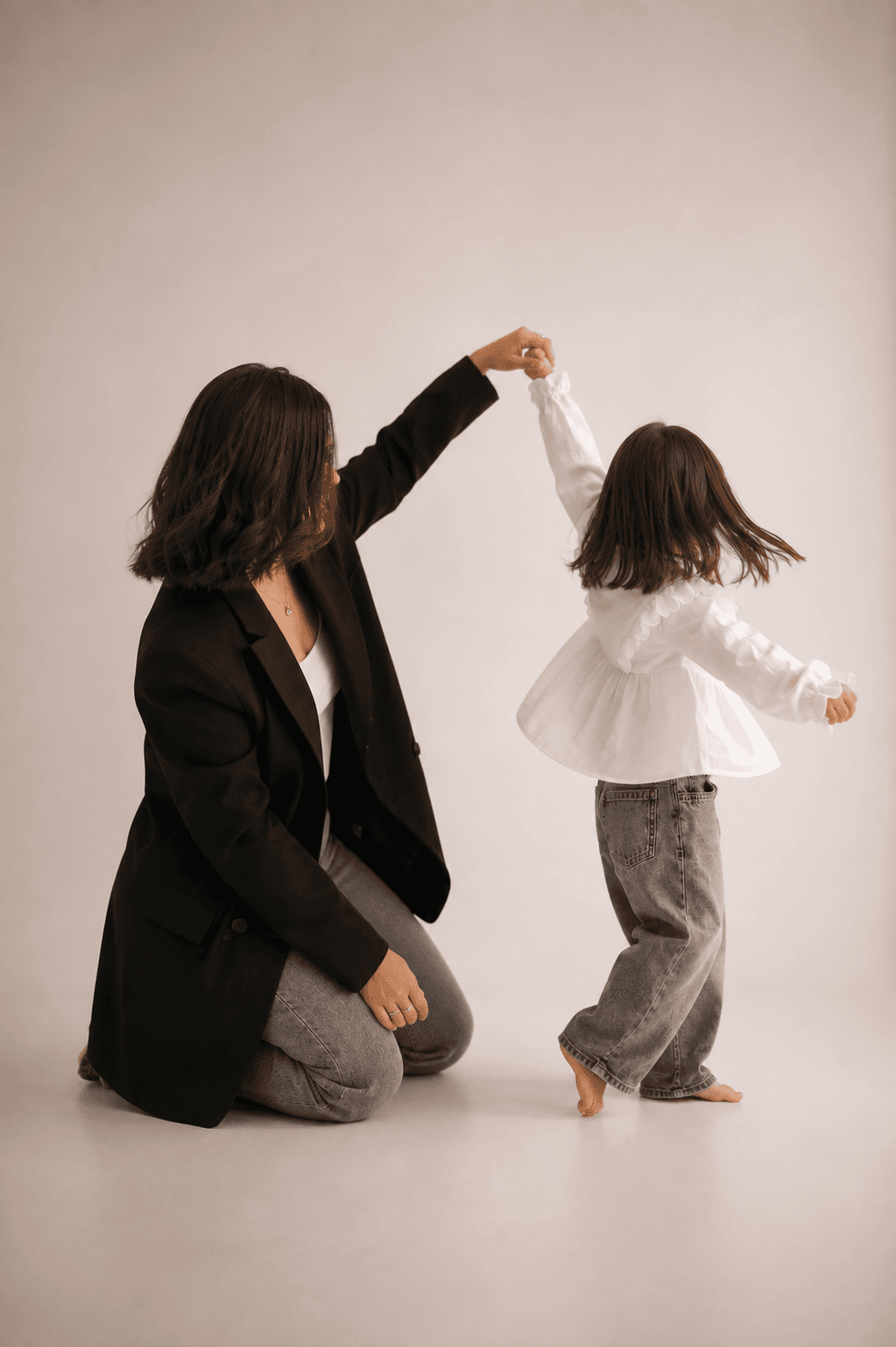 Mãe brincando com a filha em um estúdio de tons neutros